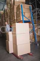 Worker pulling trolley with boxes in warehouse