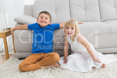 Siblings sitting on the floor and smiling at camera together