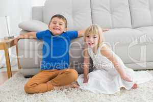 Siblings sitting on the floor and smiling at camera together