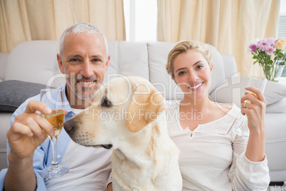 Happy couple with their pet dog drinking champagne