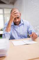 Tired businessman with paperwork at desk