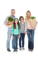 Smiling family standing holding bag of healthy groceries