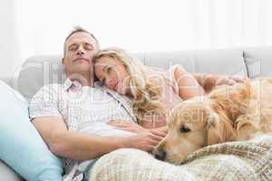 Loving couple sitting on couch with their dog
