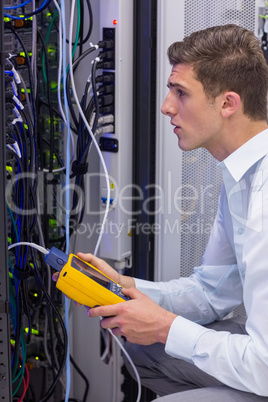 Serious technician using digital cable analyzer on server