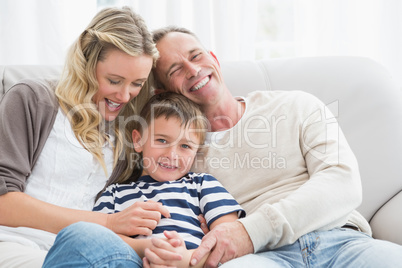 Happy parent tickling her cute son on the couch