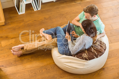 Cute couple using tablet pc on beanbag