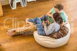 Cute couple using tablet pc on beanbag