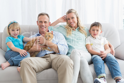Cute family relaxing together on the couch with their cat