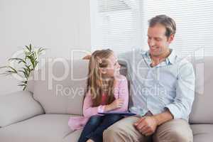 Casual father and daughter using tablet on the couch