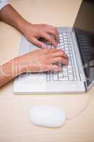 Hands using laptop at desk