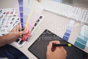 Designer using graphics tablet and colour charts