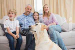 Parents and their children on sofa with puppy