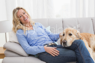 Smiling blonde woman petting her golden retriever