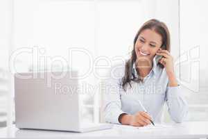 Happy businesswoman using laptop at her desk