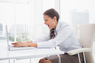 Angry businesswoman using laptop at desk
