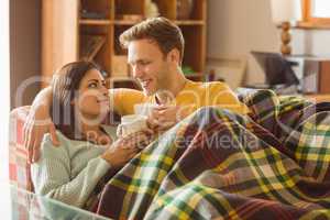 Young couple cuddling on the couch under blanket