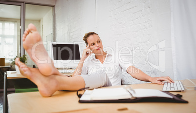 Businesswoman with legs crossed at ankle on desk