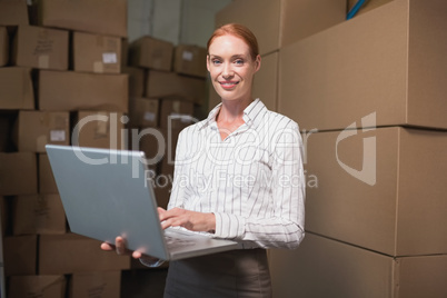 Female manager using laptop in warehouse