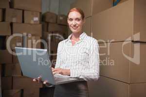 Female manager using laptop in warehouse