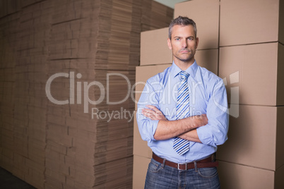 Serious manager with arms crossed in warehouse