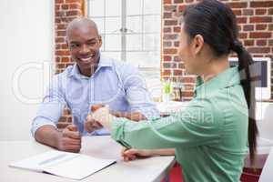 Casual business people shaking hands at desk