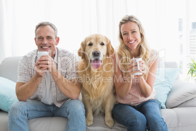 Smiling casual couple sitting on couch having coffee