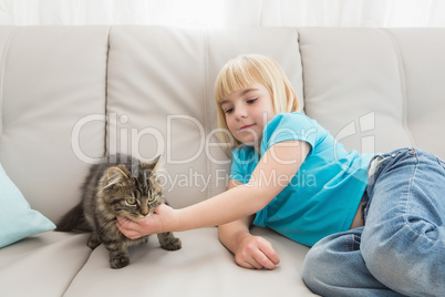 Little girl lying on the couch stroking her cat
