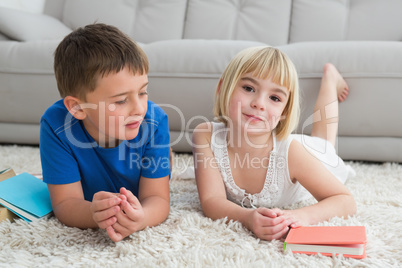 Siblings laying on the floor reading storybook