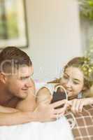 Cute couple lying on bed listening to music