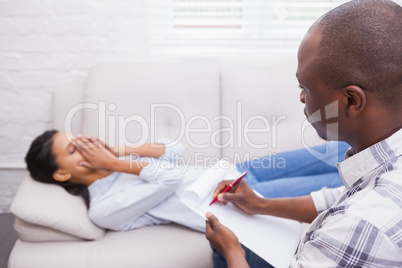 Therapist writing notes on his crying patient on the couch