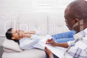 Therapist writing notes on his crying patient on the couch