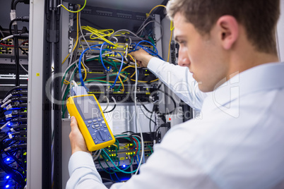 Serious technician using digital cable analyzer on server