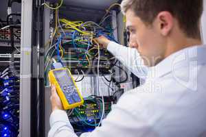 Serious technician using digital cable analyzer on server