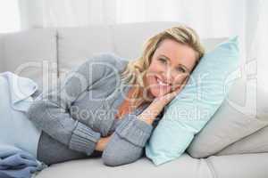Pretty smiling blonde lying on cosy sofa