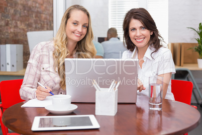 Smiling businesswomen working together with laptop