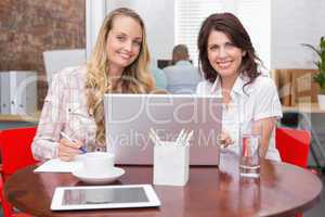Smiling businesswomen working together with laptop