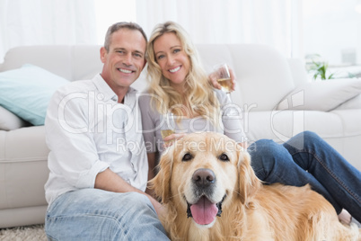 Couple drinking champagne with their dog in front of them