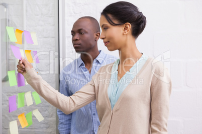 Creative business team looking at sticky notes on window