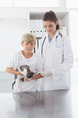 Smiling vet examining a cat with its owner