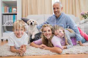 Happy parents and their children on floor with puppy