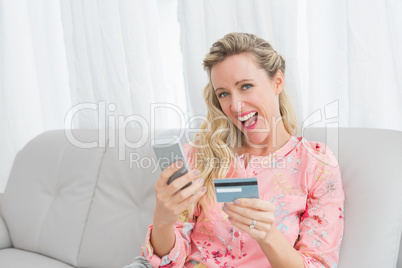 Woman looking at her credit card holding phone