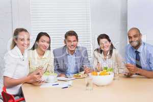 Workers smiling at camera eating sandwiches and salad