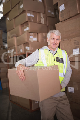 Worker carrying box in warehouse