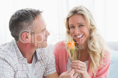 Man offering a rose to girlfriend on the couch