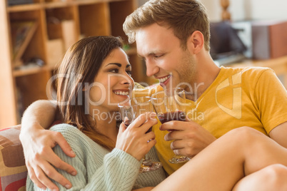 Young couple cuddling on the couch with red wine