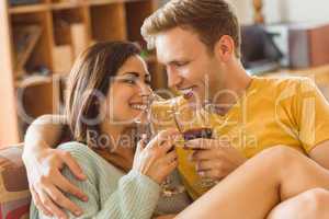 Young couple cuddling on the couch with red wine