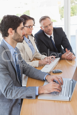 Focused team looking at a laptop