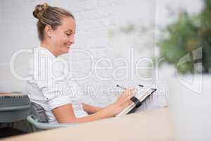 Businesswoman writing in diary at office