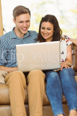 Young cute couple relaxing on couch with laptop