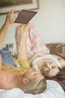 Cute couple using tablet pc in bed